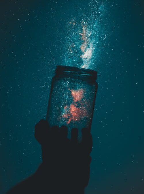 Photo of a glass jar held up so it appears to hold stars.
